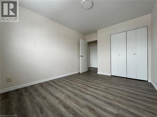 Spacious room featuring wood-finish flooring, light-toned walls, white baseboards, and a contemporary ceiling light fixture - 232 Louisa Street Unit# 9A, Kitchener, ON - Indoor Photo Showing Other Room