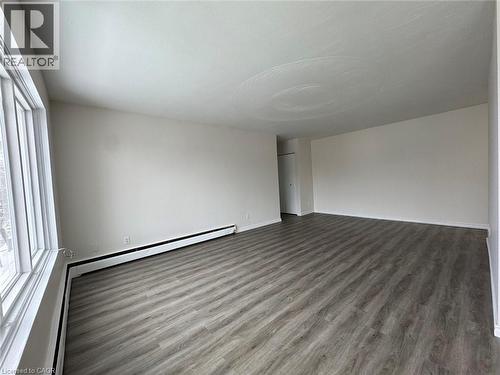 Spacious room featuring light wood-finish flooring, a broad window, and neutral wall paint - 232 Louisa Street Unit# 9A, Kitchener, ON - Indoor Photo Showing Other Room