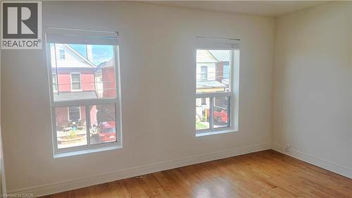 Room featuring two windows with white trim, wood-finish flooring, white walls, and white baseboards - 85 Oxford Street, Hamilton, ON - Indoor Photo Showing Other Room