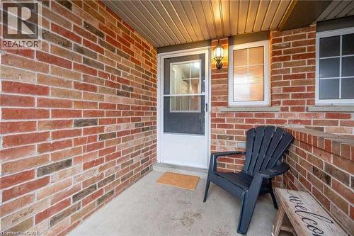 Covered front entrance featuring multi-toned brickwork, a white door with an upper glass panel, and a built-in wall lantern - 27 Max Becker Drive, Kitchener, ON - Outdoor With Exterior