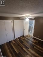 Room featuring wood-finish flooring, two sets of bi-fold closets, a ceiling fan with integrated lighting, and neutral wall paint - 