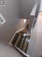 Staircase featuring wood-finish treads and risers, white trim, and a partial wood handrail - 
