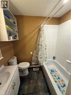 Bathroom featuring a white vanity with integrated sink, white toilet, and a white tub with white tile surround - 