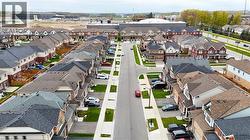 Aerial perspective showcasing a residential street lined with multi-story townhomes, each featuring individual driveways and small landscaped front yards - 