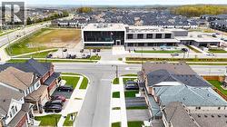 Modern multi-story building featuring expansive window panels, a paved parking area, and an adjacent athletic field - 