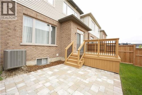 Outdoor patio featuring light-toned paver stones, a wooden deck with dark balusters, and a sliding glass door leading indoors - 11 William Dunlop Street, Kitchener, ON - Outdoor With Deck Patio Veranda With Exterior
