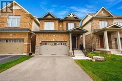 Brick facade home featuring a covered front entry with stairs and railing, an attached garage, and a paved driveway - 