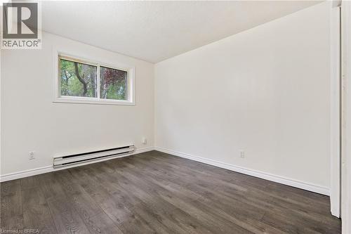 Bright interior space featuring wood-finish flooring, white walls, and a window with a white frame - 9 Cherry Street, Simcoe, ON - Indoor Photo Showing Other Room