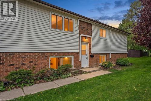 Two-story residence featuring brick and siding exterior, a front entry door with an overhead light fixture, and a concrete walkway - 9 Cherry Street, Simcoe, ON - Outdoor