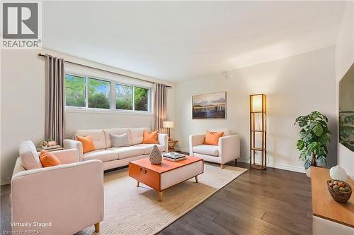 Spacious living area featuring expansive windows, wood-finish flooring, a light-toned area rug, and neutral wall paint - 9 Cherry Street, Simcoe, ON - Indoor Photo Showing Living Room
