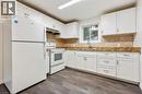 Kitchen featuring white cabinetry, a mosaic tile backsplash, wood-finish flooring, a stainless steel sink, and white appliances - 9 Cherry Street, Simcoe, ON  - Indoor Photo Showing Kitchen 