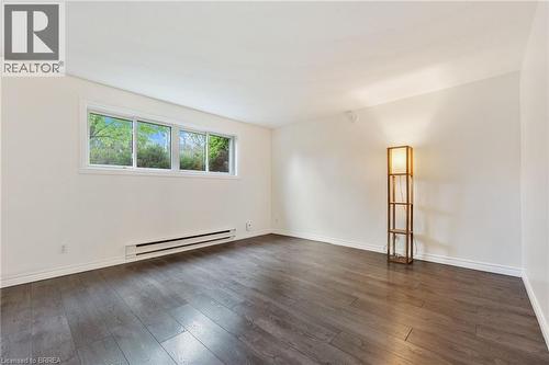 Spacious room with dark wood-finish flooring, white walls, and bright window - 9 Cherry Street, Simcoe, ON - Indoor Photo Showing Other Room