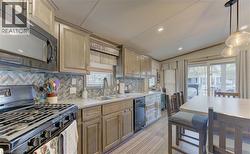 Modern kitchen featuring stainless steel appliances, a herringbone tile backsplash, and light-toned cabinetry - 