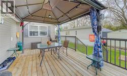 Expansive wood-finish deck featuring a metal-framed gazebo with a fabric canopy and string lighting - 