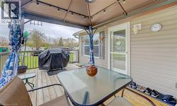 Spacious wooden deck featuring a gazebo, privacy curtains, metal railings, and attached outdoor lighting - 