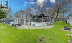 Exterior featuring a raised deck with railing, a storage shed, a gravel patio area with stepping stones, and a fire pit with a stone surround - 