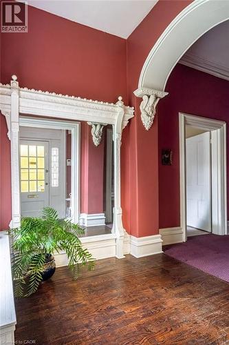 Entryway featuring dark wood-finish flooring, an ornate white archway, decorative white trim, and a white paneled door with glass inserts - 370 Hess Street S, Hamilton, ON - Indoor Photo Showing Other Room