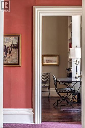 Architectural doorway with substantial white trim opens to a room featuring dark wood-finish flooring and built-in shelving - 370 Hess Street S, Hamilton, ON - Indoor