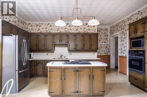 Spacious kitchen featuring extensive dark wood cabinetry, white countertops, and a central island with an integrated cooktop - 370 Hess Street S, Hamilton, ON - Indoor Photo Showing Kitchen With Double Sink