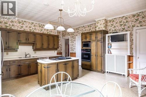 Kitchen featuring wood-finish cabinetry, an integrated wall oven and microwave, a center island, and a built-in shelving unit - 370 Hess Street S, Hamilton, ON - Indoor Photo Showing Kitchen With Double Sink