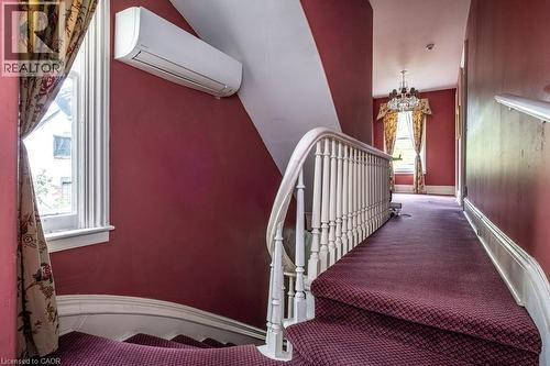 Staircase featuring a white wooden balustrade and a wall-mounted air conditioning unit - 370 Hess Street S, Hamilton, ON - Indoor Photo Showing Other Room