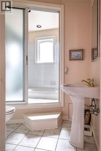 Bathroom featuring a pedestal sink with brass-finish faucet, tile flooring, and a sliding frosted glass shower enclosure - 370 Hess Street S, Hamilton, ON - Indoor Photo Showing Bathroom