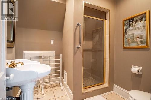 Bathroom featuring a pedestal sink with a gold-finish faucet, a glass-enclosed shower with gold-tone framing, and neutral wall paint - 370 Hess Street S, Hamilton, ON - Indoor Photo Showing Bathroom