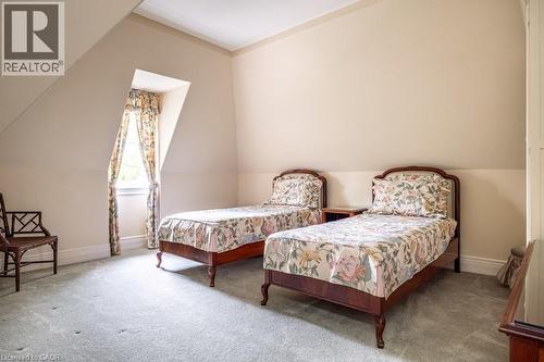 Sloped ceiling room featuring a window with patterned drapes, light-toned walls, and grey carpeting - 370 Hess Street S, Hamilton, ON - Indoor Photo Showing Bedroom