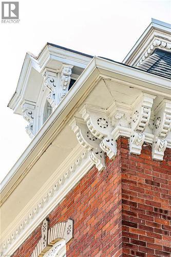 Detailed architectural elements featuring red brick construction, ornate white corbels, decorative fascia, and a prominent roofline - 370 Hess Street S, Hamilton, ON - 