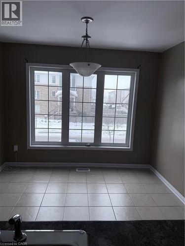 Spacious interior featuring a large multi-pane window, ceramic tile flooring, a semi-flush mount light fixture, and a dark countertop - 50 Emick Drive, Ancaster, ON - Indoor Photo Showing Other Room