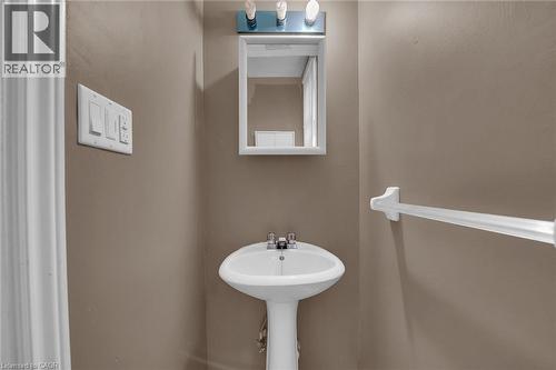 Pedestal sink with chrome faucet set beneath a medicine cabinet and vanity light fixture - 738 King Street W, Hamilton, ON - Indoor Photo Showing Bathroom