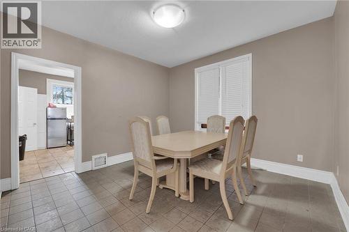 Dining area featuring neutral wall paint, tiled flooring, a window with horizontal blinds, and a ceiling-mounted light fixture - 738 King Street W, Hamilton, ON - Indoor Photo Showing Dining Room