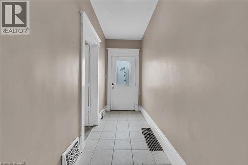 Hallway featuring neutral wall paint, white trim, white paneled door with frosted glass, and light-toned tile flooring - 738 King Street W, Hamilton, ON - Indoor Photo Showing Other Room