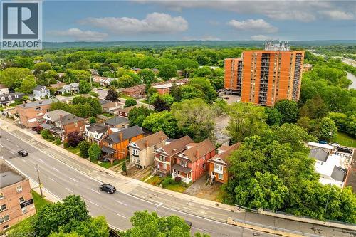 Aerial perspective showcasing a residential street with diverse architectural styles, mature trees, and a distant high-rise building - 738 King Street W, Hamilton, ON - Outdoor With View