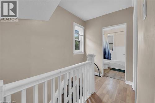 Upper landing featuring light-toned walls, wood-finish flooring, and white painted railings - 738 King Street W, Hamilton, ON - Indoor Photo Showing Other Room