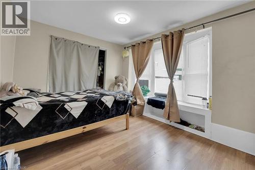 Room featuring wood-finish flooring, a contemporary flush-mount ceiling light, and neutral wall tones - 738 King Street W, Hamilton, ON - Indoor Photo Showing Bedroom