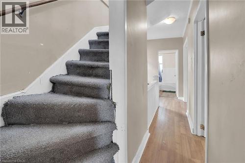 Staircase featuring grey carpeting and a wooden handrail - 738 King Street W, Hamilton, ON - Indoor Photo Showing Other Room