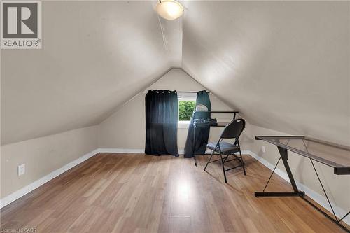 Attic space featuring wood-finish flooring, an angled ceiling, and a prominent window - 738 King Street W, Hamilton, ON - Indoor Photo Showing Other Room