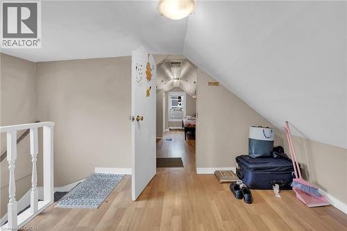 Upper-level landing featuring wood-finish flooring, a white spindle railing, and a sloped ceiling design - 738 King Street W, Hamilton, ON - Indoor Photo Showing Other Room