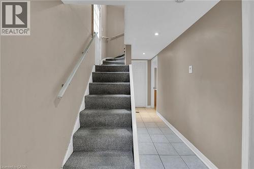 Carpeted staircase with an aluminum handrail, leading to an upper level with natural light from a window - 738 King Street W, Hamilton, ON - Indoor Photo Showing Other Room