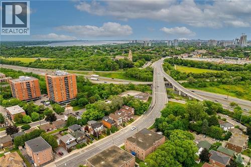 Aerial perspective showcasing an expansive urban landscape with abundant greenery, prominent roadways, and residential structures - 738 King Street W, Hamilton, ON - Outdoor With View