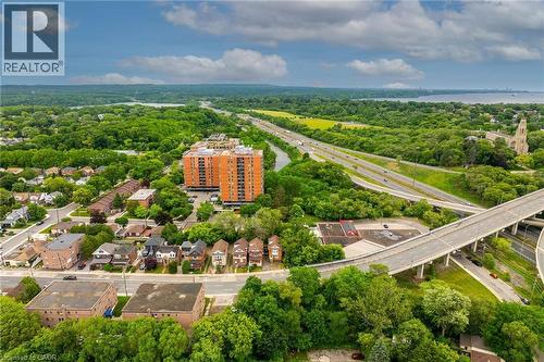Aerial perspective showcasing a multi-lane highway system, surrounding green spaces, and a residential area with a prominent high-rise building - 738 King Street W, Hamilton, ON - Outdoor With View
