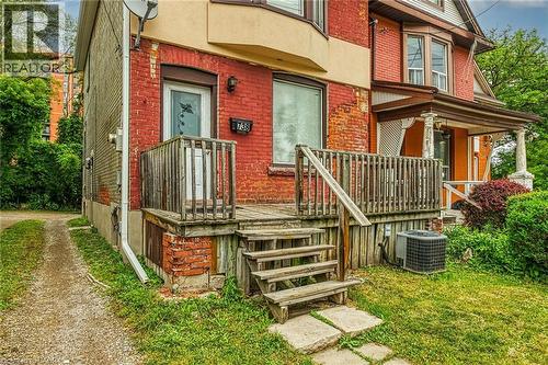 Red brick exterior with an elevated wooden porch and steps - 738 King Street W, Hamilton, ON - Outdoor