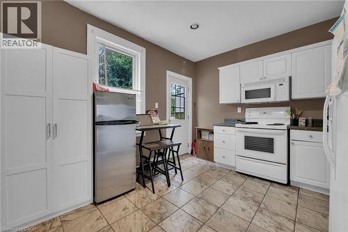 Kitchen featuring white cabinetry, a stainless steel refrigerator, white range and microwave, and patterned tile flooring - 738 King Street W, Hamilton, ON - Indoor Photo Showing Kitchen