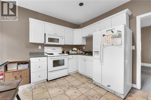 Kitchen featuring white cabinetry, a white electric range, a white microwave, a white side-by-side refrigerator, and stone-finish countertops - 738 King Street W, Hamilton, ON - Indoor Photo Showing Kitchen