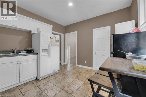 Kitchen featuring white cabinetry, a stainless steel sink, tiled flooring, and neutral wall paint - 738 King Street W, Hamilton, ON - Indoor