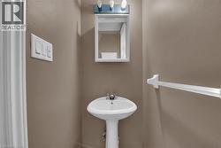 Pedestal sink with chrome faucet set beneath a medicine cabinet and vanity light fixture - 