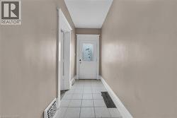 Hallway featuring neutral wall paint, white trim, white paneled door with frosted glass, and light-toned tile flooring - 