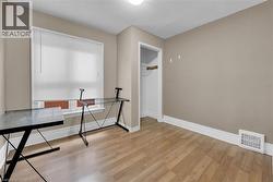 Room featuring wood-finish flooring, a window with blinds, and neutral wall paint - 