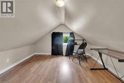 Attic space featuring wood-finish flooring, an angled ceiling, and a prominent window - 